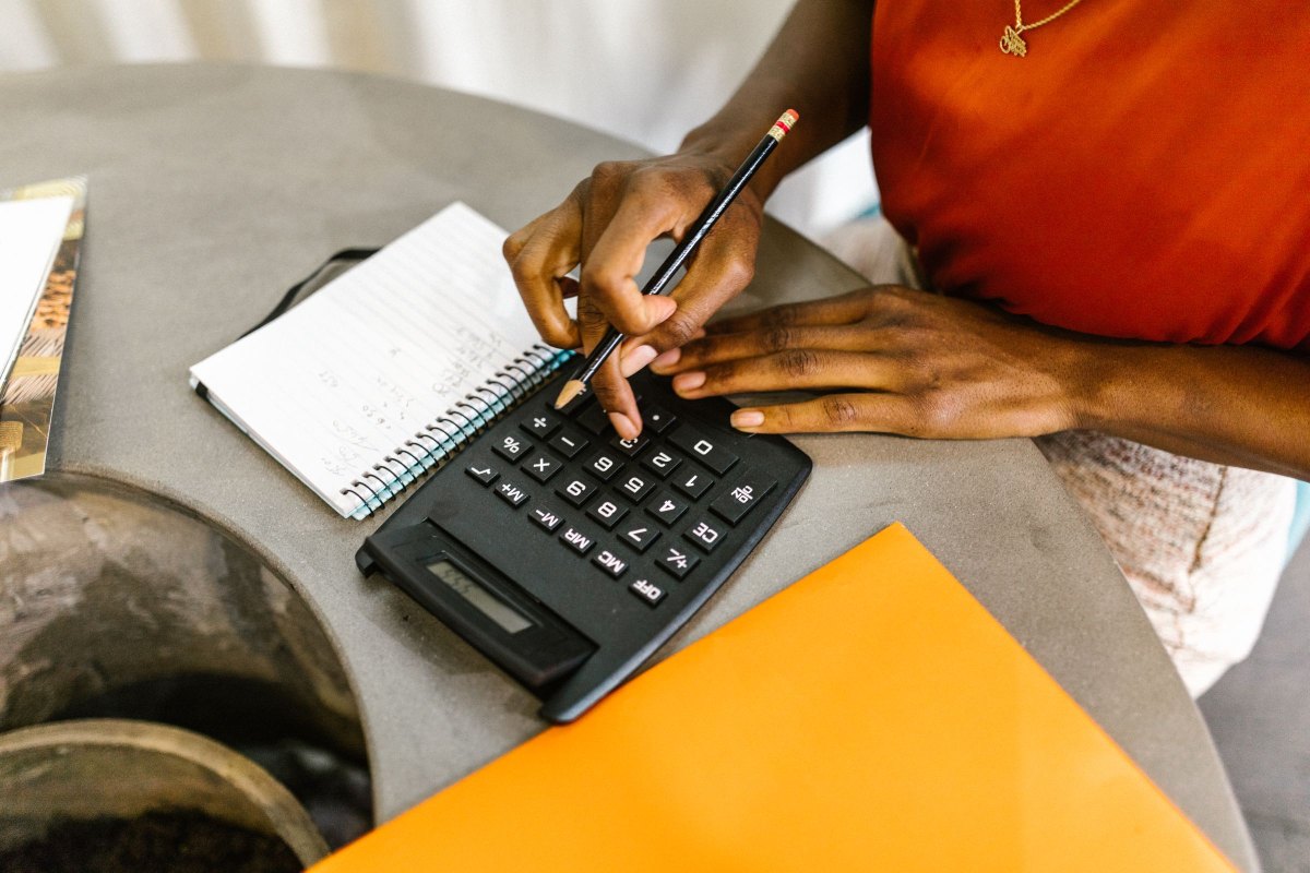 Hands using a calculator next to a notebook