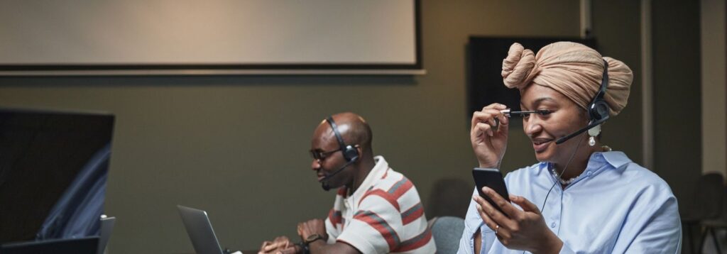 Call centre agents with headsets working at laptops