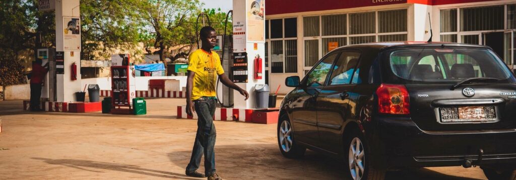 Petrol attendant walking to a car at a fuel station forecourt