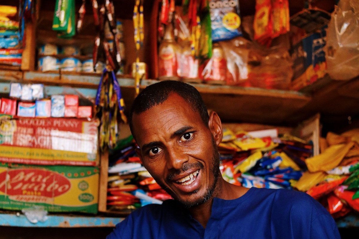 Shop owner standing behind the counter of his small shop
