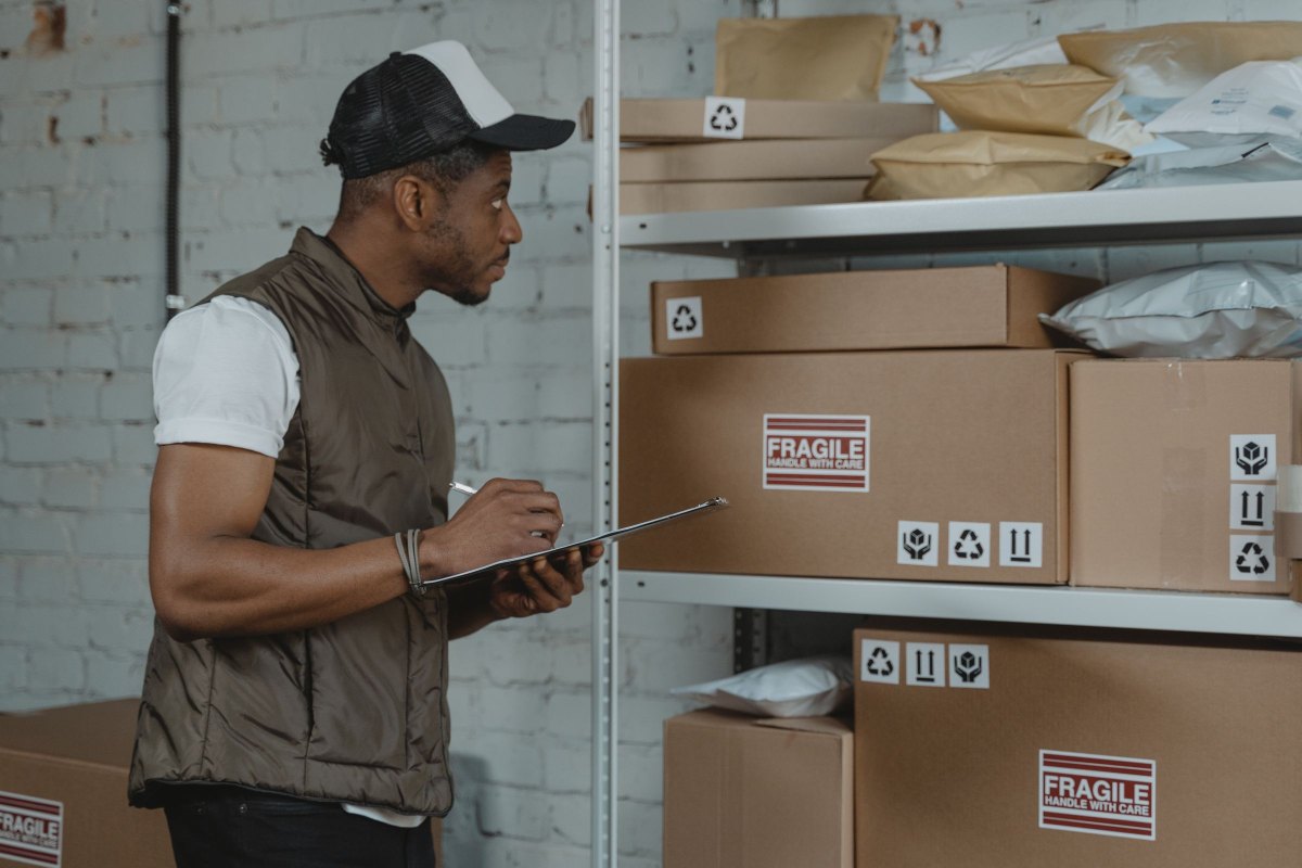 Stock clerk checking boxes with a clipboard in a warehouse