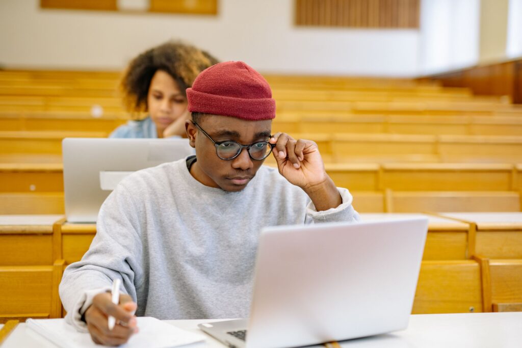 Young man working on his CV on a laptop and taking notes